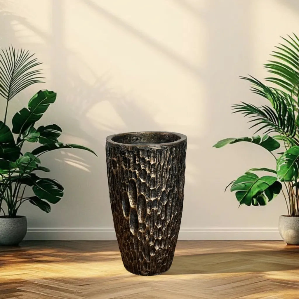 Decorative textured plant pot on a wooden floor with plants on either  black-gold-stone-fiberglass-pot-plantmartpkside.