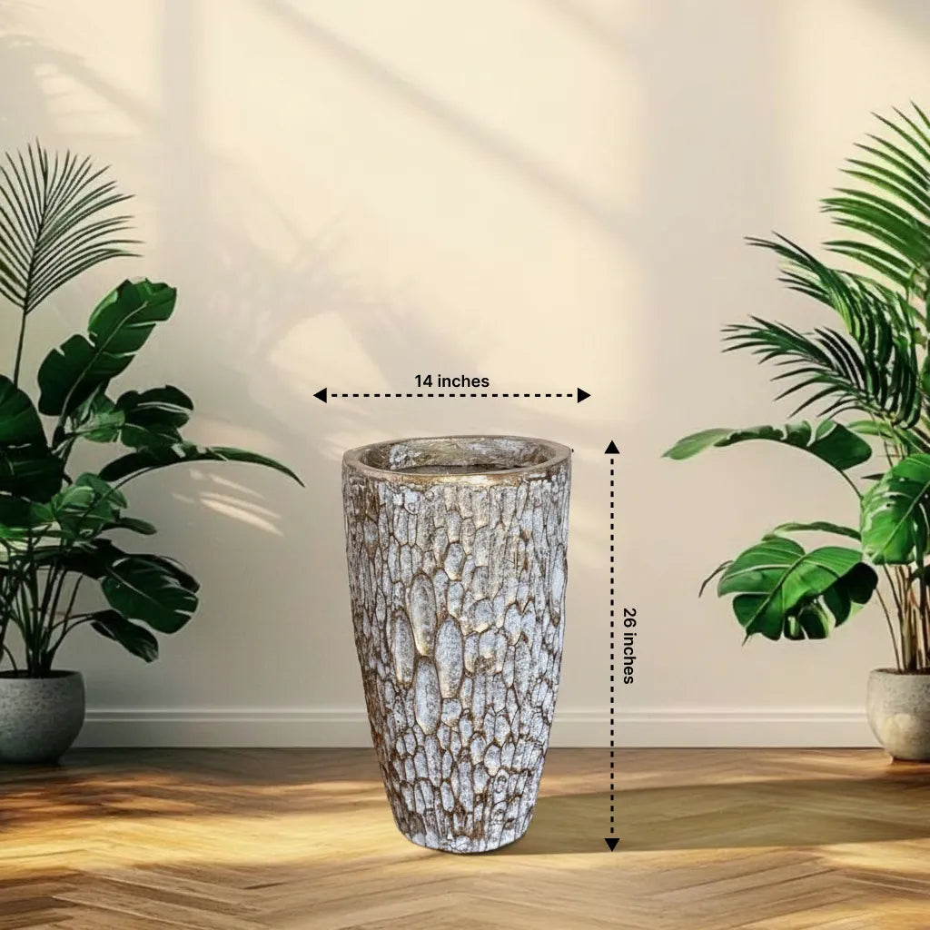 Decorative tall planter with dimensions labeled, placed between two potted plants on a wooden floor.
